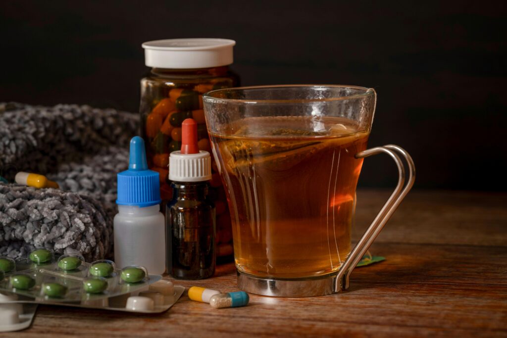 A cup of herbal tea with medications suggests natural cold remedies for healing.