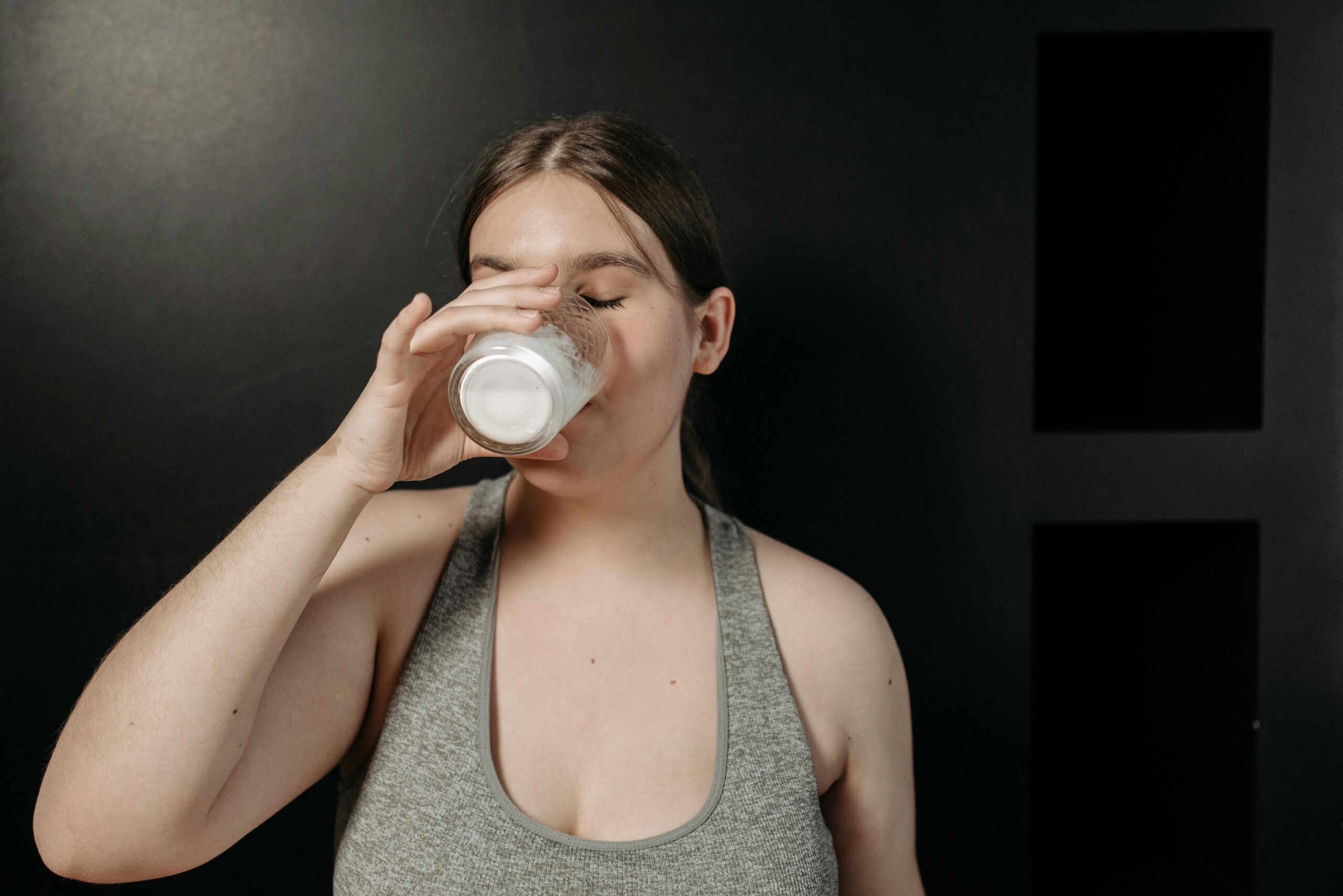 A woman in a sports top enjoying a glass of milk for health and fitness.