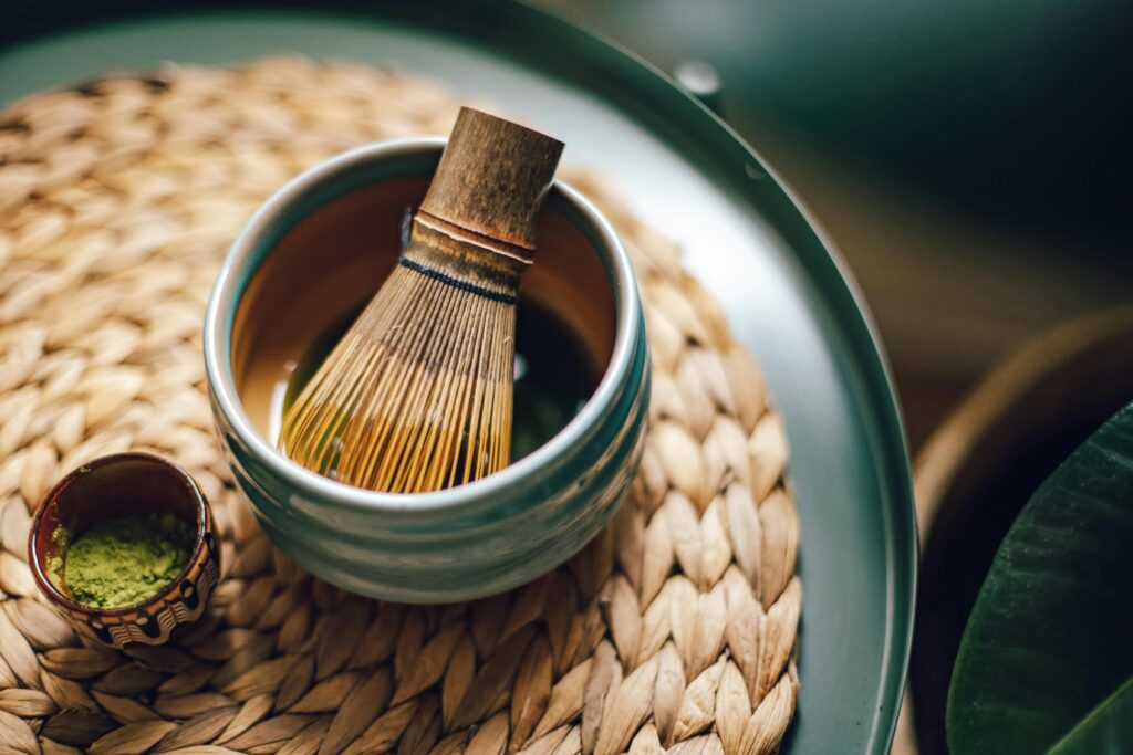 Close-up of bamboo whisk and matcha powder, highlighting traditional tea tools.