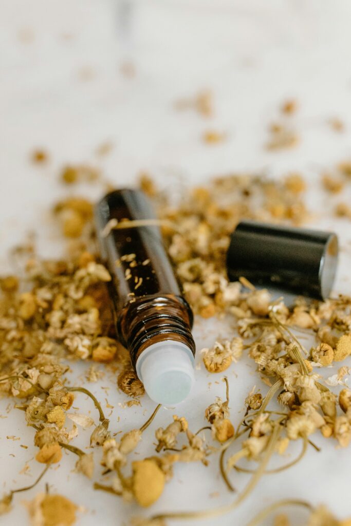 Aromatic essential oil bottle alongside dried chamomile flowers, perfect for natural and holistic concepts.